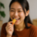 Young woman smiling while eating, showing natural teeth alignment and healthy smile.