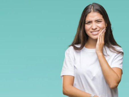 Woman holding her cheek in discomfort from wisdom tooth pain.