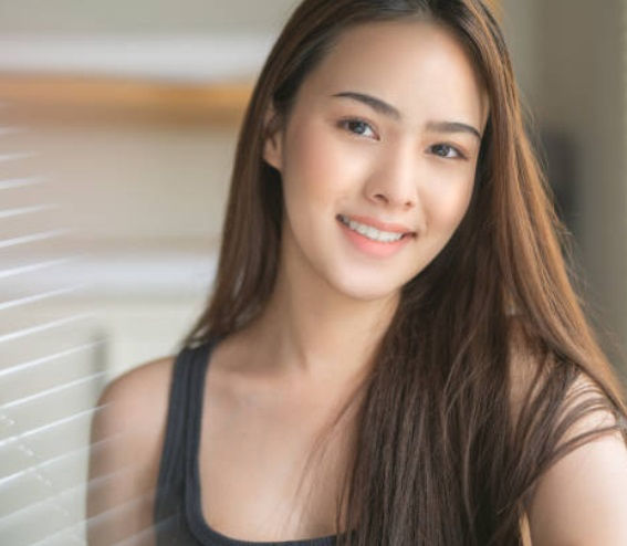 Happy woman in Singapore smiling confidently after resolving gum pain with professional dental care.
