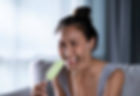 Woman holding her cheek in pain while holding an ice lolly, illustrating tooth sensitivity or pain