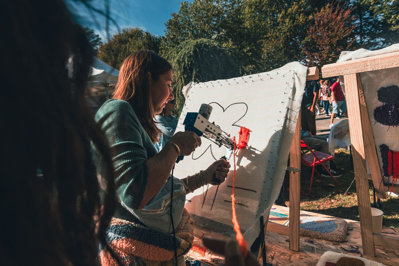 Une invitée tufte un motif lors d'un événement en extérieur