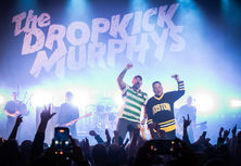 Photo with cool color tones of senate candidate Graham Platner on stage with Dropkick Murphy's