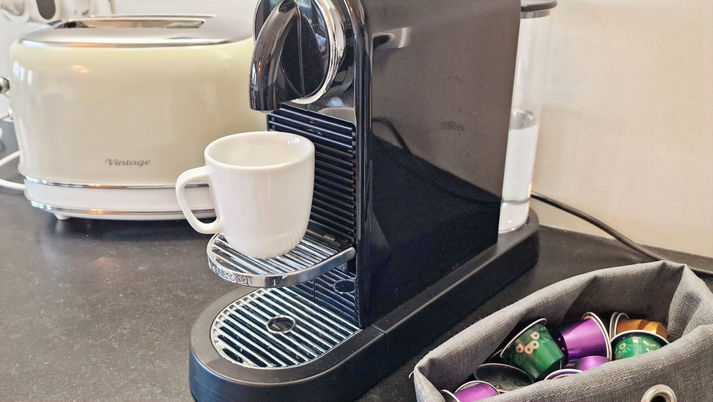 Gros plan sur la cuisine du studio Les Cristaux à Combloux avec machine à café Nespresso noire, capsules colorées et grille-pain crème vintage.