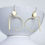 Thumbnail: Gold statement, earrings, and white ceramic bowl with white background.