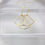 Thumbnail: Directly overhead face on view of the flutter necklace on top of a clear resin rectangle prop. Background is off white. 
