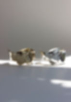 Thumbnail: Side view of silver and gold tone cuffs on dappled light background. 