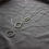 Thumbnail: Three layered geometric silver necklaces on a gray velvet background. The light is dark and muted.