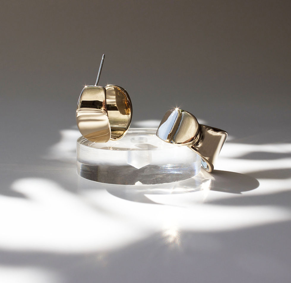 Thumbnail: Gold tone wide hoops on dappled light background with small clear resin prop. 
