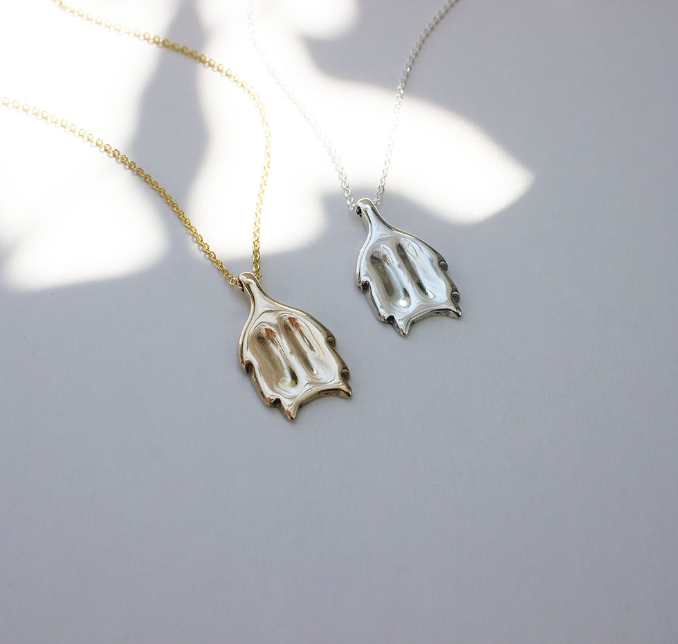 Thumbnail: Silver and gold tone necklace on a dappled light off-white background.