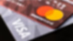 Close-up of overlapping credit cards: red Mastercard with orange and red circles, white text; gray Visa with white text.