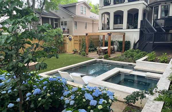 lush plantings surrounding a beautiful in ground pool with a spa spillover water feature, a pergola with outddining area.