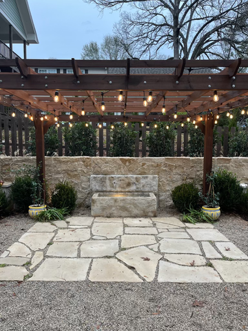 outdoor lighting on a pergola with water feature on stone patio