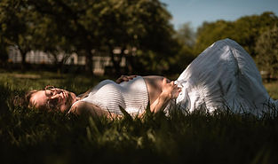 Zwanger vrouw ligt in het gras tijdens een zwangerschapsshoot in Frederiksoord.