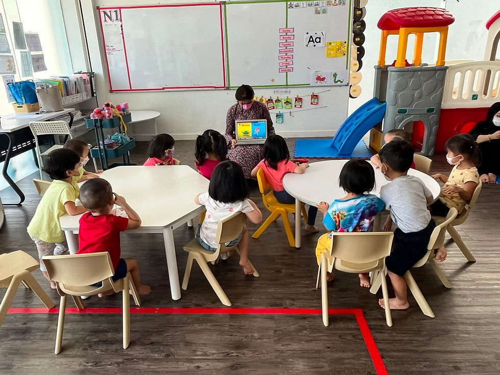 A teacher sharing a picture book with children seated around classroom tables