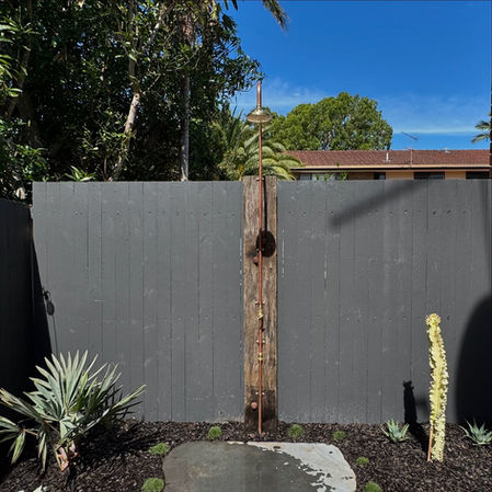 Rustic outdoor shower against dark fence