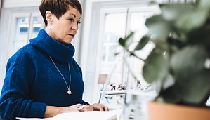 Kvinna som sitt på kontoret och jobbar med en dator.