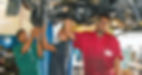 Auto Mechanic Present trainee on job training (red coverall)together with past trainee in