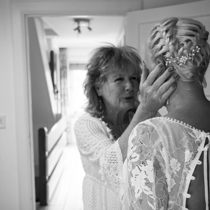 Bruiloft J&Q voorbereiding-Moeder die haar dochter vasthoudt en geëmotioneerd is door het aantrekken van de jurk