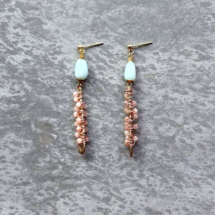 Blue Peruvian Opal Rose Quartz Earring on stone background.