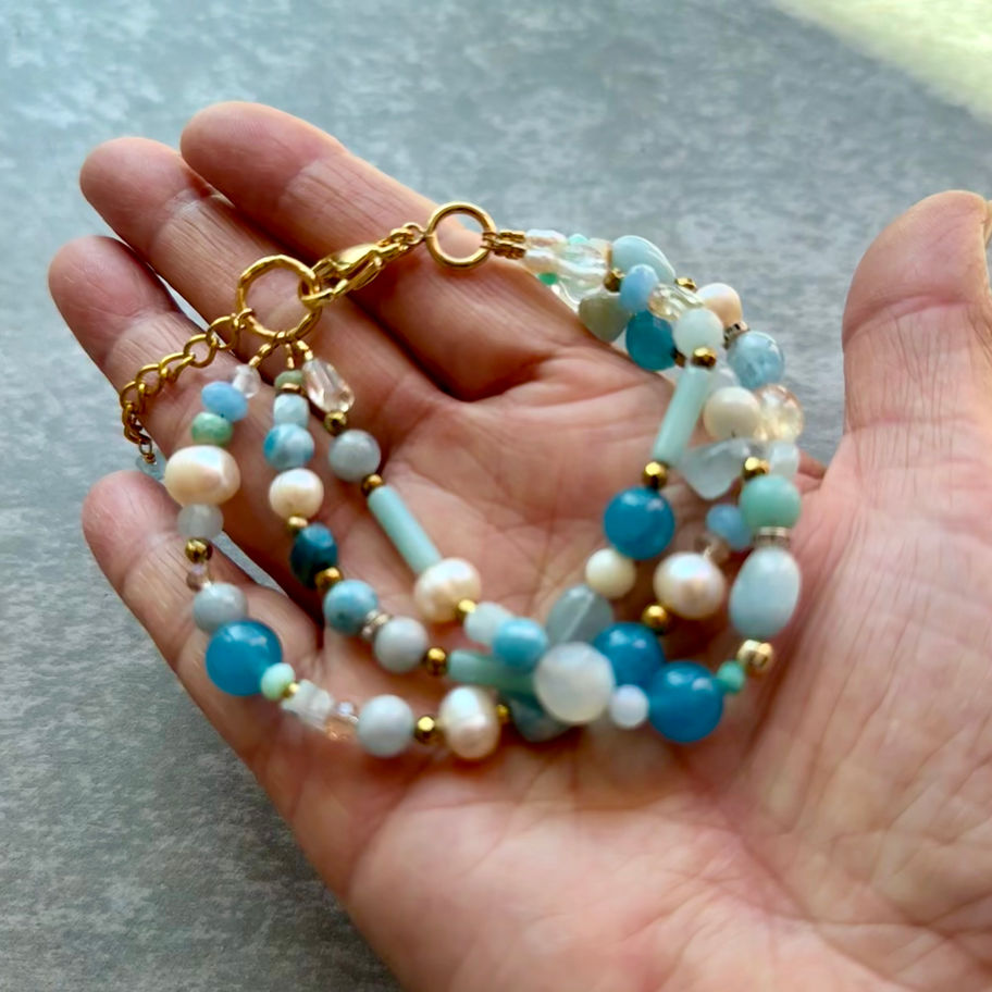 Larimar and Aquamarine Gemstone Bracelet featuring three strands of blue gemstones and white pearls.
