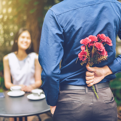 The man is hiding red flowers behind him in order to surprise his girlfriend.jpg