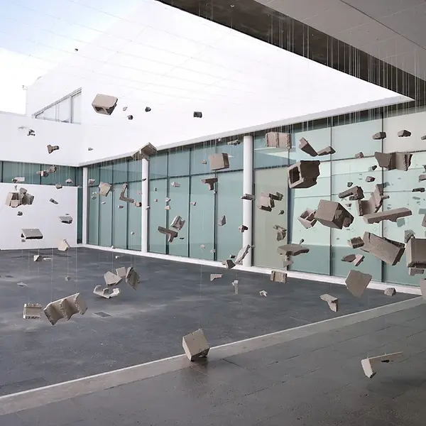 Sala del Museo de Arte de Zapopan con una obra de arte conceptual que parece romper la gravedad, con elementos dispersos en el espacio.