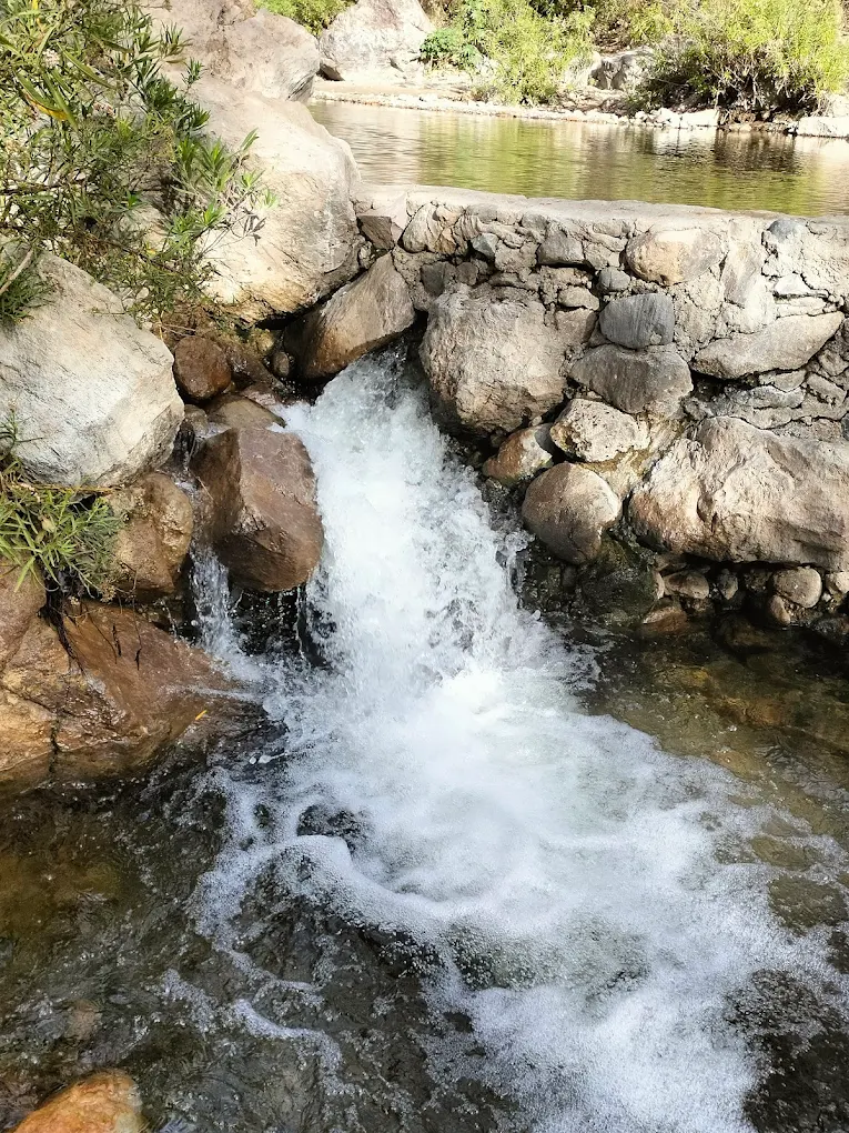 Corriente de agua blanca del Río Caliente deslizándose entre rocas.