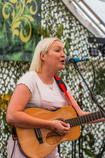 A woman sings and plays guitar