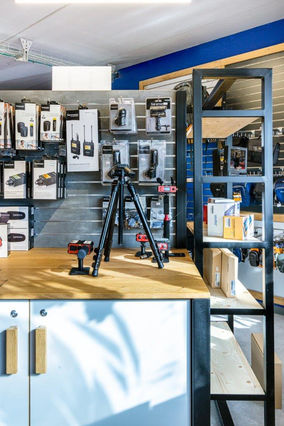 עמדות תצוגה מברזל ועץ בשילוב פורמייקה לבנה, ידיות עץ, קיר לתליית אביזרים ומוצרים פורמייקה דמוי בטון