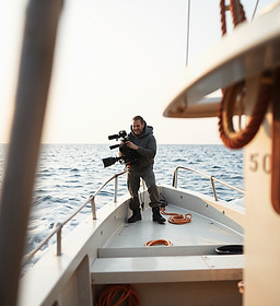a vertical image of a cameraman on a smaller size work boat out in the ocean_edited.jpg