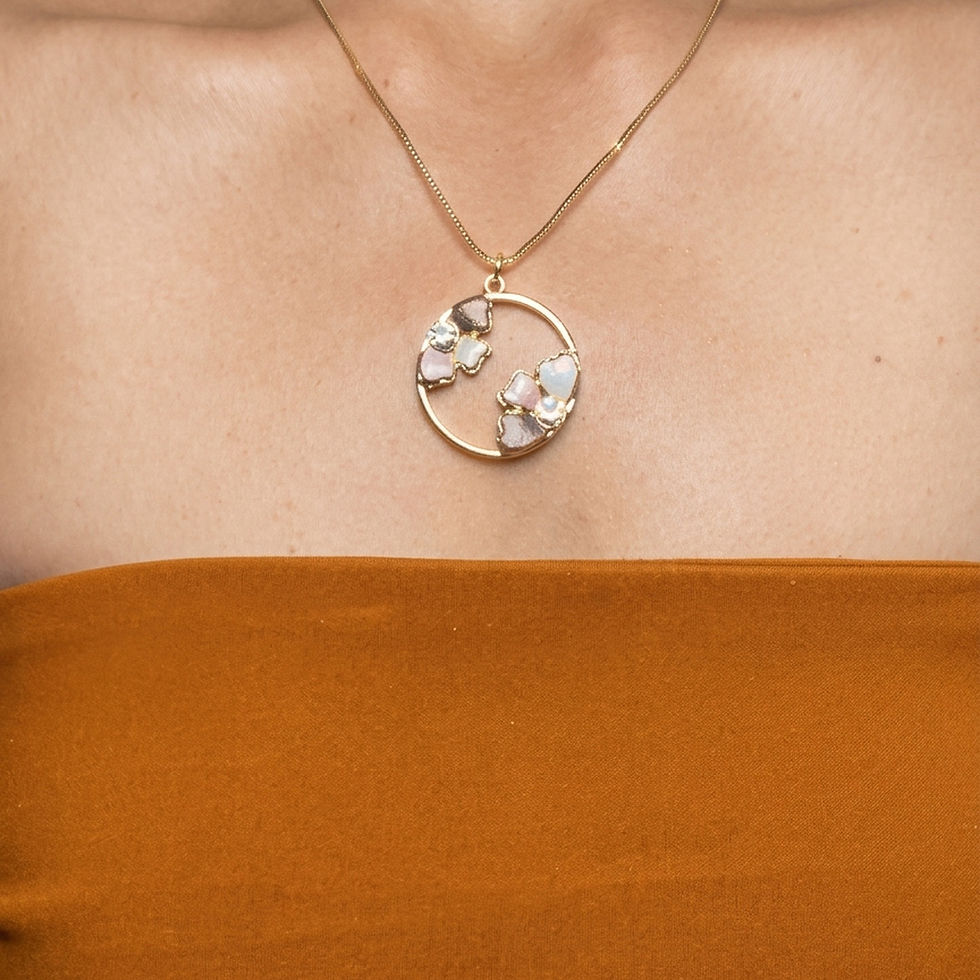 Enamel flower necklace with an open gold circle pendant holding two flowers in plum, pink and white, worn below the collarbon