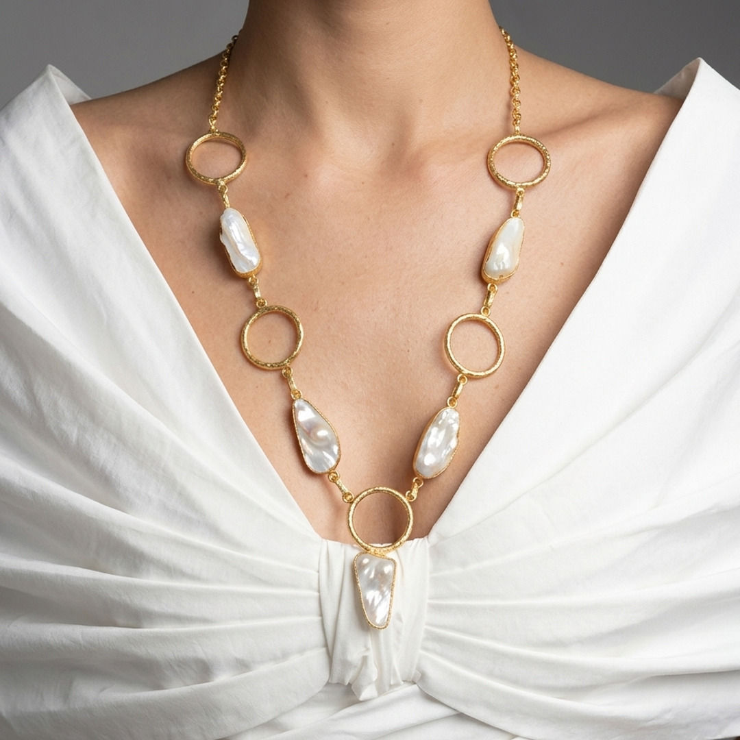 Mother of pearl pendant necklace with hammered gold rings and five bezel-set stones worn in a long V, white fabric