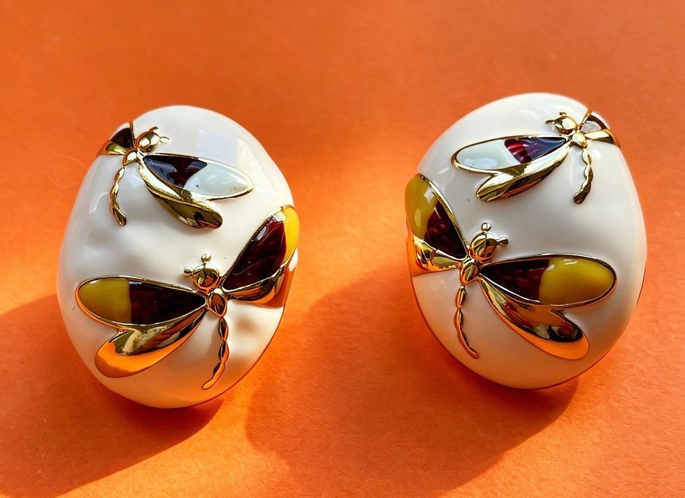 A pair of The Evelyn White Enamel Dragonfly Earrings with a domed white enamel design and gold dragonfly motif.