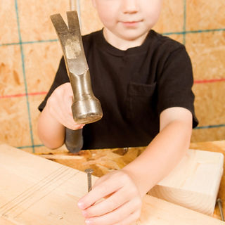 Child using real hammer, montessori method to use real tools