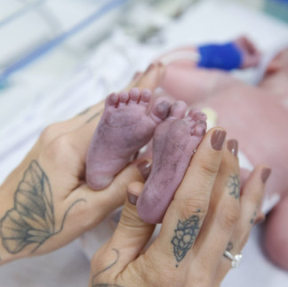 Recém-nascido Dom segura o dedo da mãe após o nascimento, marcando a chegada do primeiro filho de Lauana Prado.