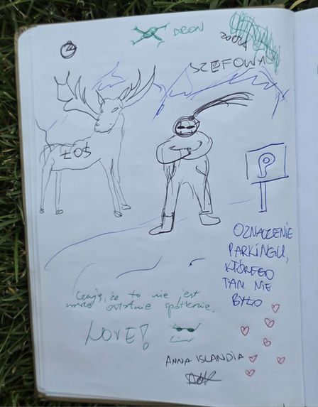 Na zdjęciu widać otwarty notes położony na trawie, z widoczną ręcznie napisaną opinią uczestniczki wyjazdu skierowaną do Julii. Na opinii znajduje się ręcznie rysowany obraz Julii podpisany szefowa oraz łoś. Tekst napisano niebieskim długopisem.
Tekst z obrazka (OCR):
Czuję, że to nie jest nasze ostatnie spotkanie.
Love!
Anna Islandia