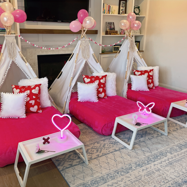 Heart-themed slumber party teepees in shades of pink and red, with heart-shaped pillows, love-themed signage, and XOXO garlands for a Valentine's-style celebration.