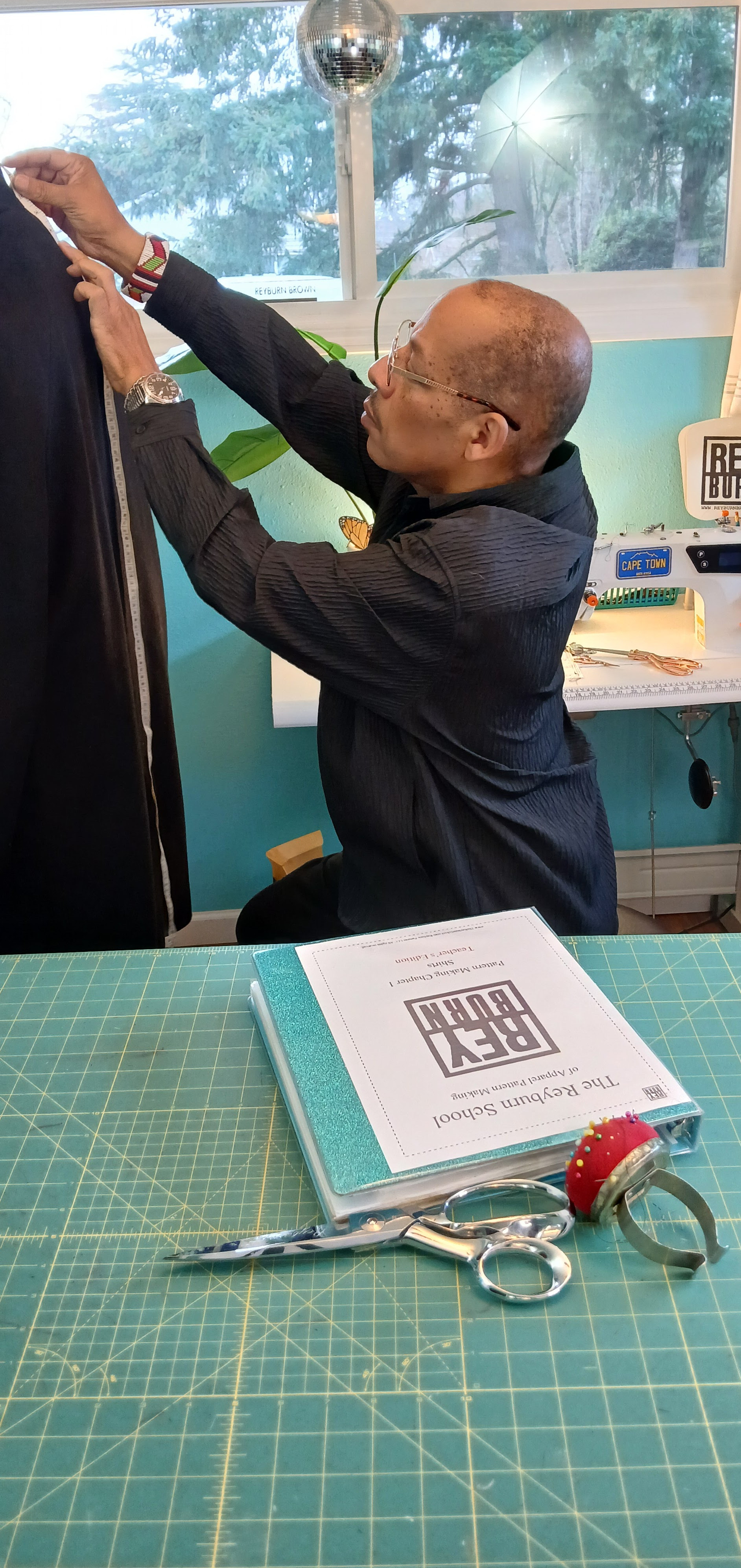 Eye-level view of a bespoke tailor measuring fabric on a wooden table