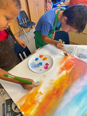 Children painting with brushes and watercolors, colorful art on white paper in the class.
