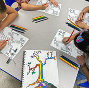 Children creating art, coloring tree drawings with crayons at a table.