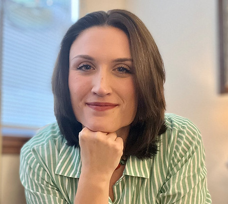 Photo of Megan Secrest, LCSW, with chin on fist, sitting, smiling at camera