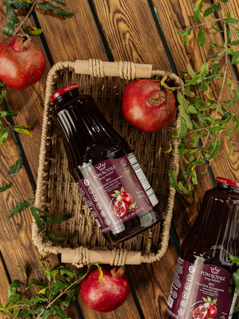 “Pom Royale pure pomegranate juice bottle styled with pomegranates”