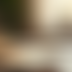 Cup of coffee next to a blank notebook and laptop