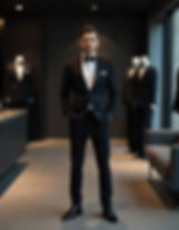 stylish man dressed in a black-tie look posing inside a suit store