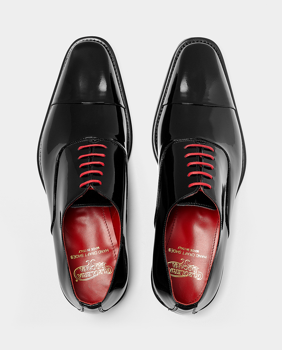 Black patent leather cap-toe oxford dress shoes with vibrant red laces and a red interior lining (top view shot)