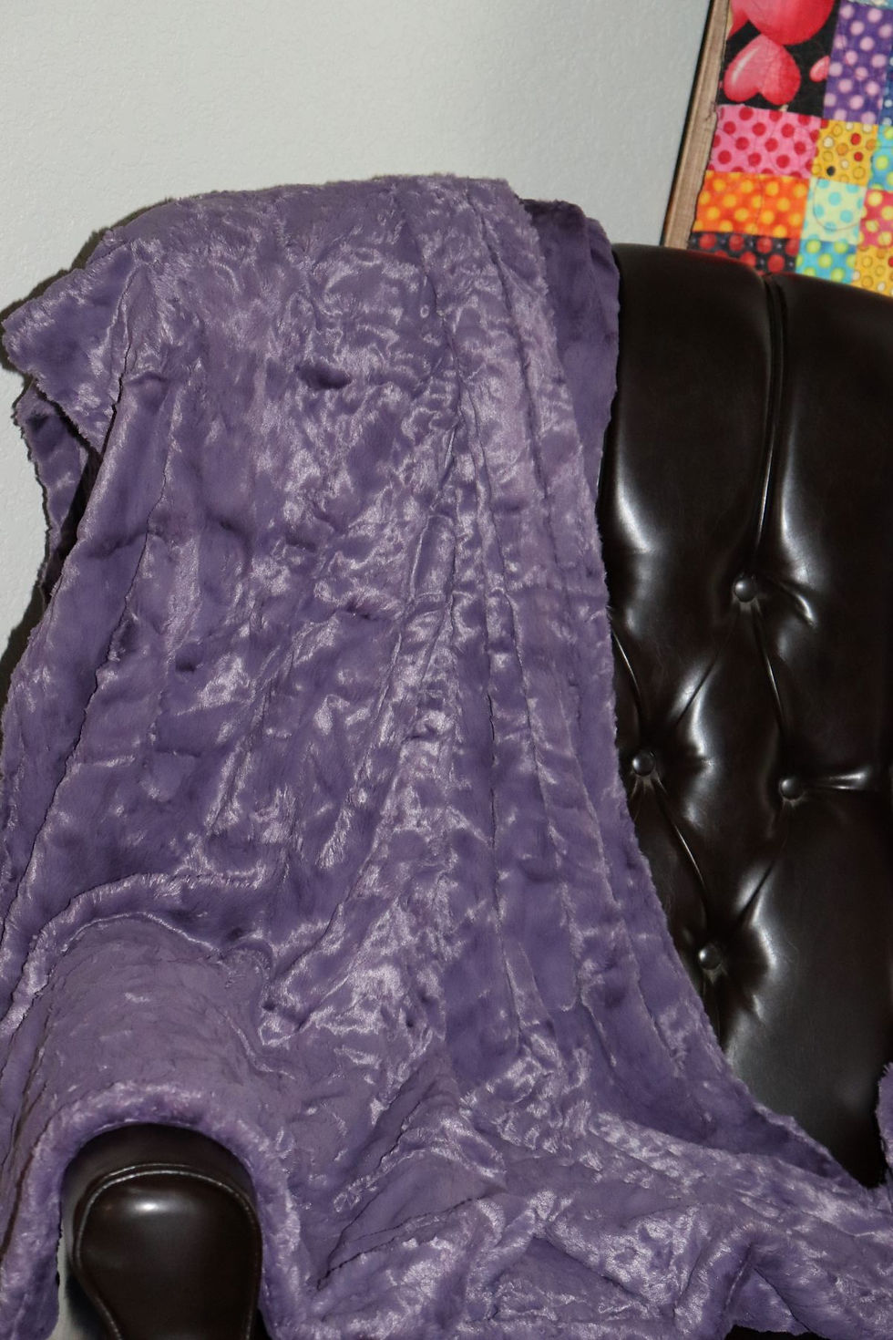 Wisteria Shadows Luxe Minky blanket draped over leather armchair, rich purple cuddle fabric with textured finish