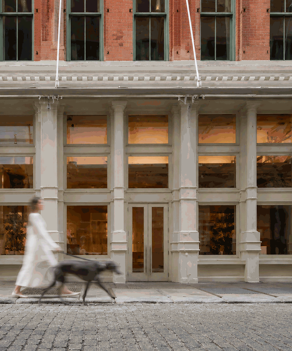 A figure dressed in white walks in SoHo NYC with an elegant black greyhound
