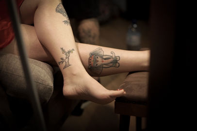 Mulher sentada com pernas tatuadas à mostra