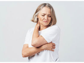 Mature woman gently stretching her neck with a pained expression, illustrating neck stiffness and discomfort common among adults aged 55+.