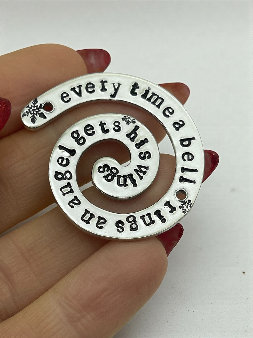 Thumbnail: hand holding hand stamped spiral ornament every time a bell rings
